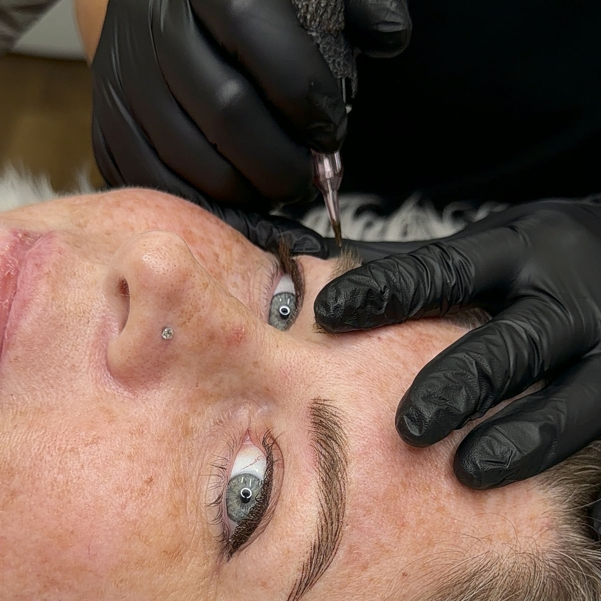 Brows being refined during a permanent makeup session